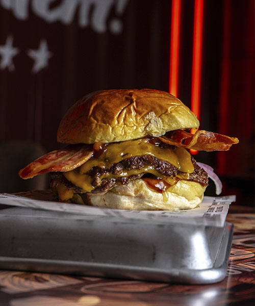 Fotografía de hamburguesa doble con bacon y queso, capturada por La Pecera para campañas visuales de marcas de comida urbana y fast food.