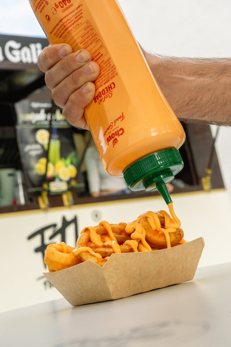 Fotografía de comida callejera con patatas rizadas y salsa cheddar, producida por La Pecera para destacar visualmente marcas de food trucks y hostelería.