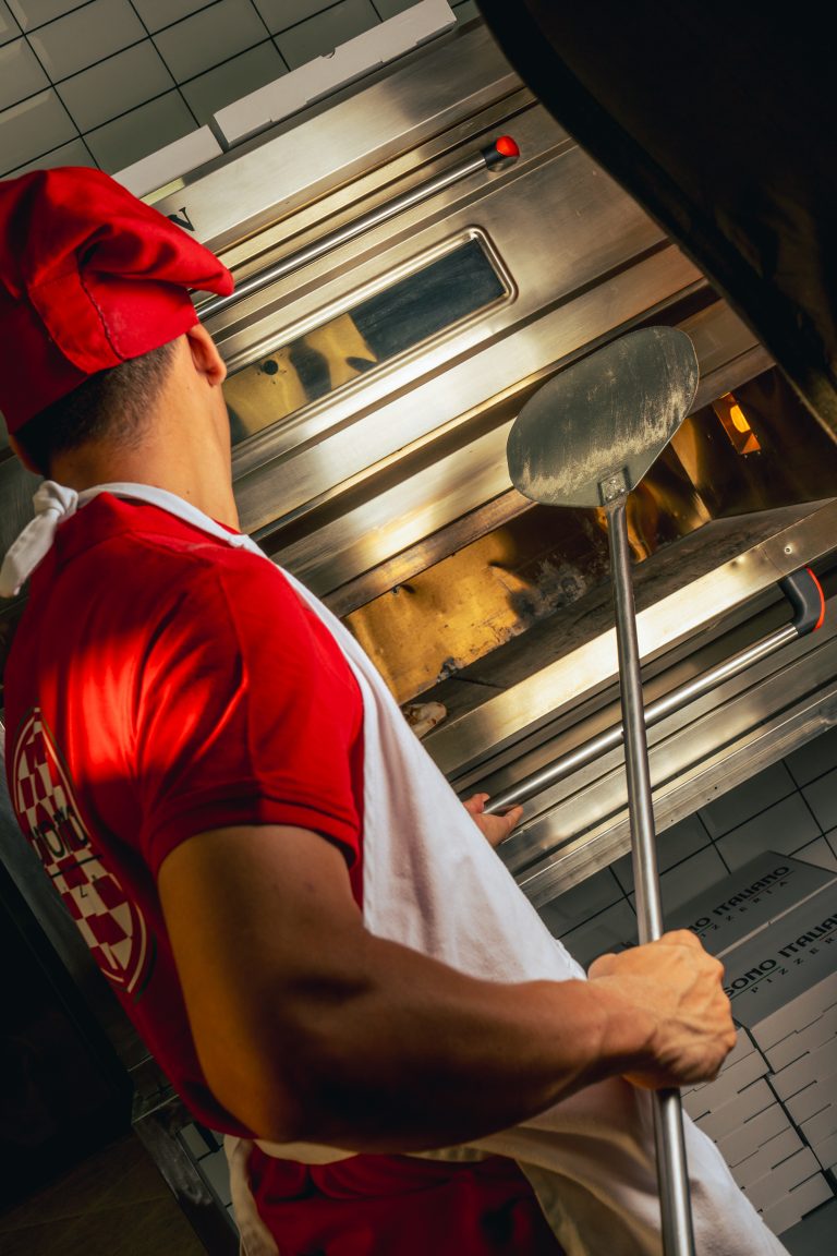 Fotografía de cocinero preparando pizzas en horno industrial, realizada por La Pecera como parte de la identidad visual de una marca del sector restauración.